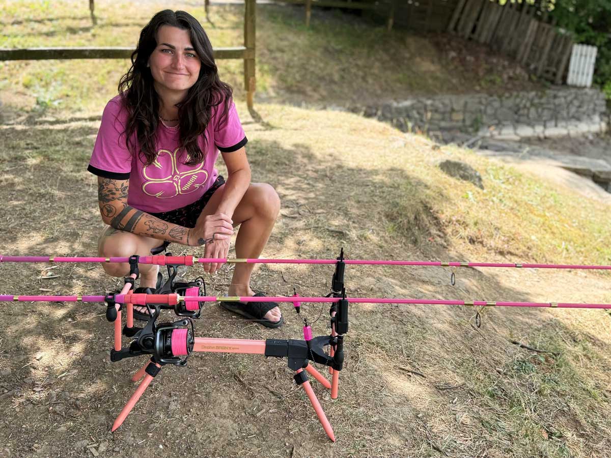 Anglerin mit pinker Delphin QUEEN Angelausrüstung, Karpfenruten, Rollen und Rod Pod am Angelplatz