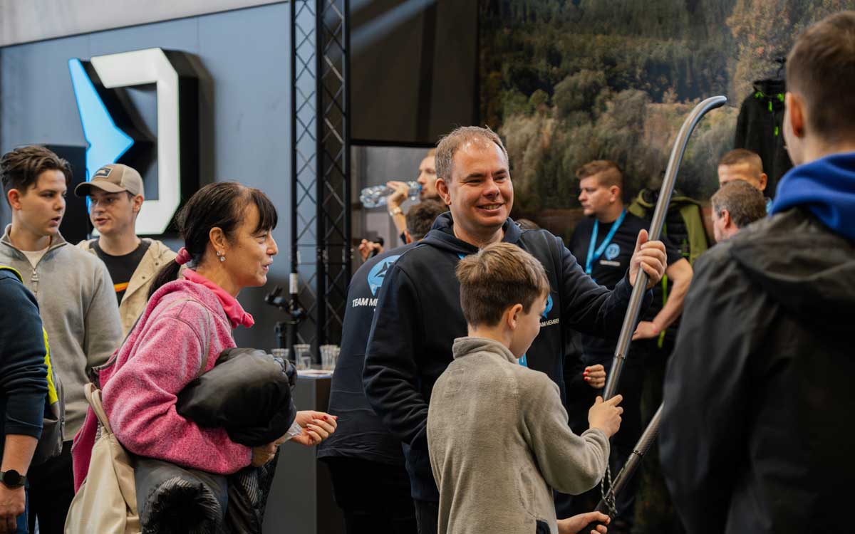 Delphin-Mitarbeiter zeigt Besuchern und Kindern ein Wurfrohr am Delphin Fishing Messestand