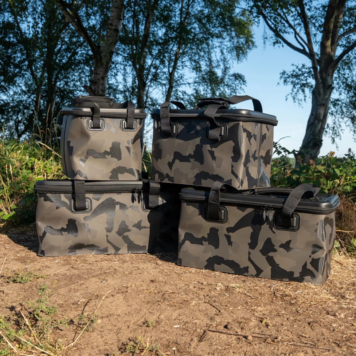 Drei Avid-Carp-Stormshield-Camo-EVA-Taschen mit Tarnmuster am Seeufer