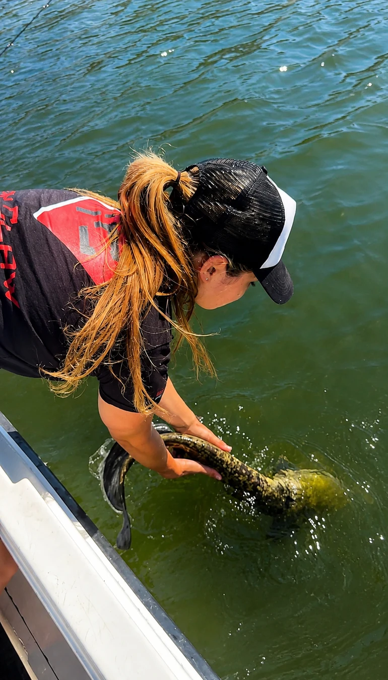 Anglerin beim Zurücksetzen eines Fisches am Boot