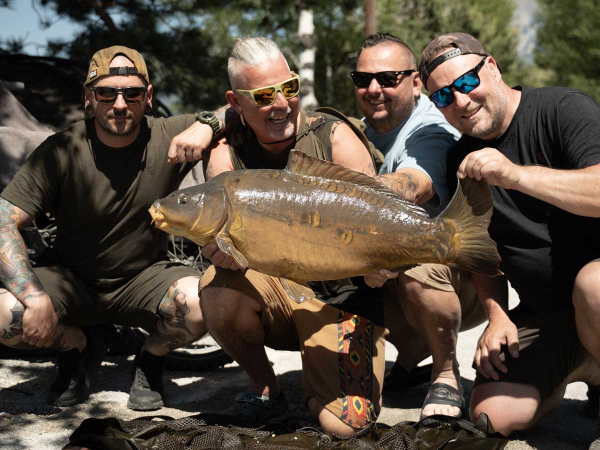 Four anglers holding up a big mirror carp together.