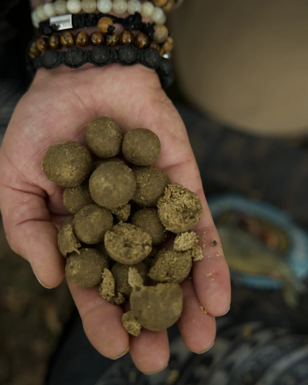 Whole and broken-open boilies in a hand, showing their structure.