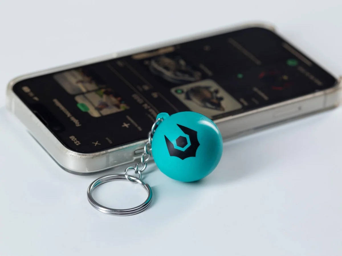 Türkisfarbener Vampire Magic Ball mit Schlüsselring neben einem Smartphone